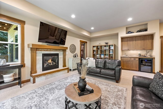 living room featuring a fireplace, indoor wet bar, beverage cooler, light carpet, and recessed lighting