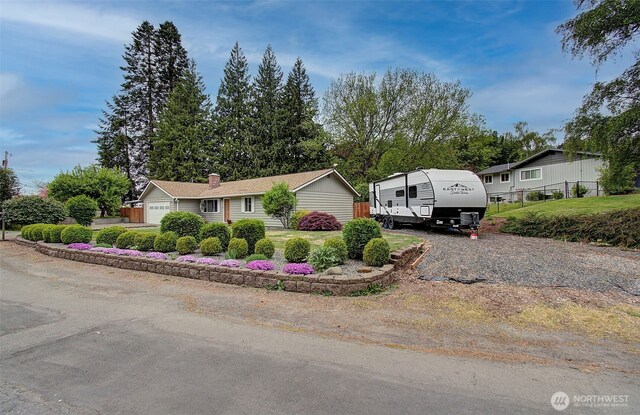 view of front of house with fence, a chimney, and a garage