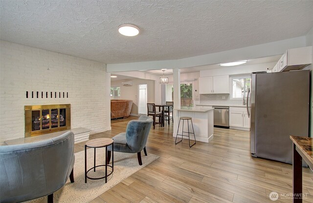 living room with a fireplace, light wood-type flooring, and a textured ceiling