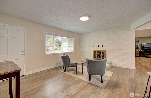 sitting room with a textured ceiling, baseboards, and wood finished floors