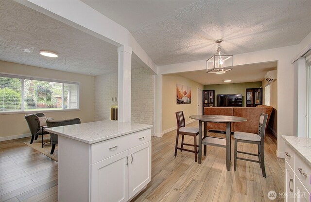 kitchen with light wood-style flooring, a textured ceiling, and a wall unit AC