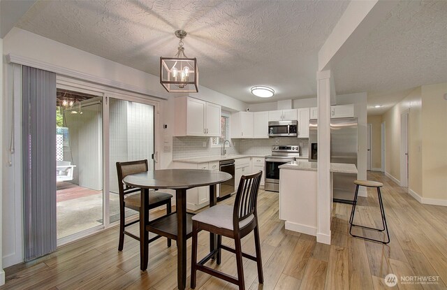 kitchen featuring backsplash, a textured ceiling, a sink, light countertops, and stainless steel appliances