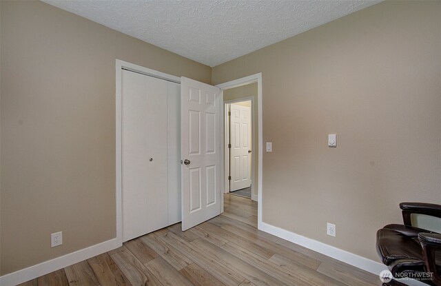 office with a textured ceiling, baseboards, and light wood-style flooring