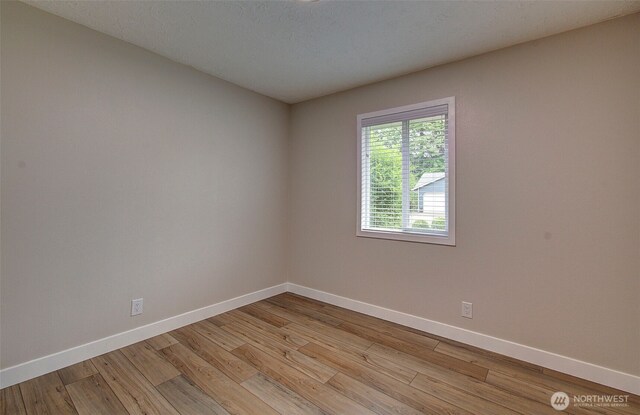 spare room with light wood-style floors and baseboards