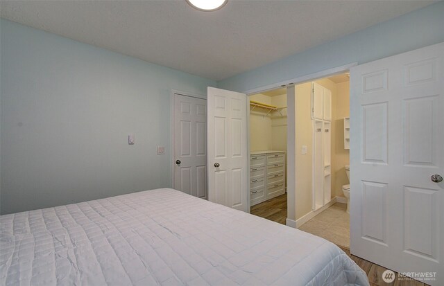 bedroom with baseboards, a walk in closet, and a closet