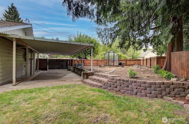 view of yard with an outdoor structure, a patio, a fenced backyard, an exterior structure, and an attached carport