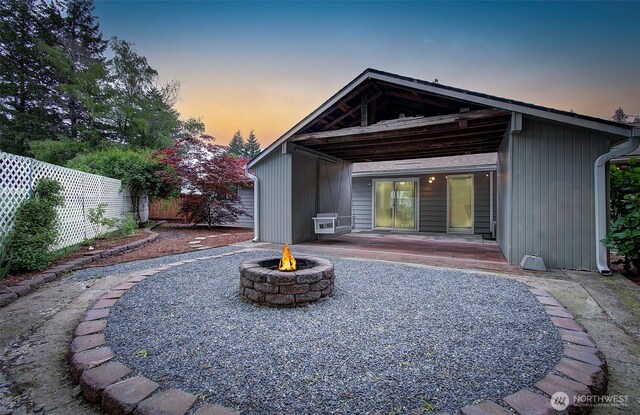 back of house at dusk featuring fence and an outdoor fire pit