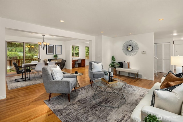 living room with a chandelier, plenty of natural light, light wood-type flooring, recessed lighting, and baseboards