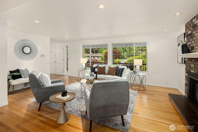 living room featuring a brick fireplace, plenty of natural light, light wood-type flooring, and recessed lighting