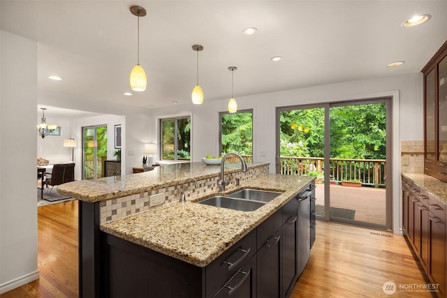 kitchen with a sink, a kitchen island with sink, plenty of natural light, recessed lighting, and light wood-type flooring