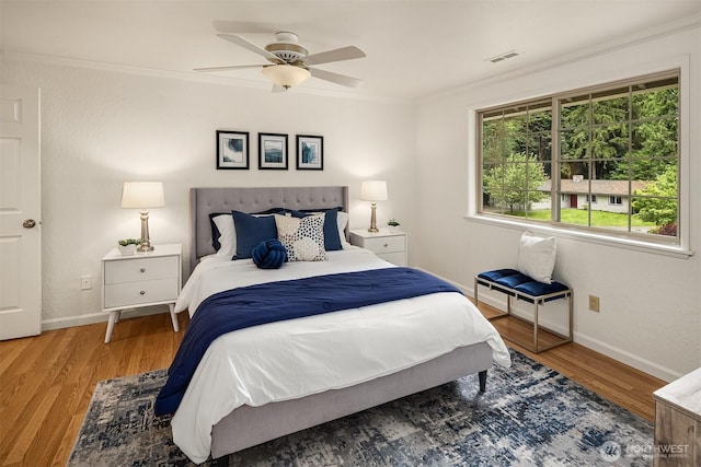 bedroom featuring ornamental molding, baseboards, wood finished floors, and ceiling fan