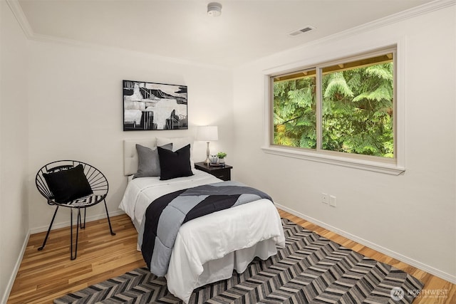bedroom with wood finished floors, baseboards, and crown molding