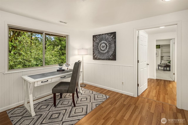 office space with light wood-style floors, a wainscoted wall, and baseboards