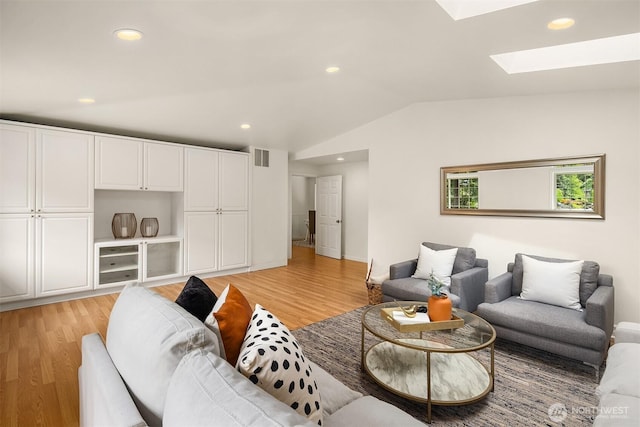 living room with a skylight, light wood finished floors, recessed lighting, and vaulted ceiling