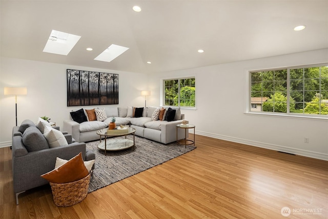 living area with a skylight, wood finished floors, baseboards, recessed lighting, and vaulted ceiling