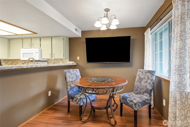 dining room with wood finished floors, baseboards, and an inviting chandelier