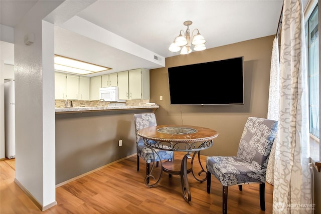 dining room with an inviting chandelier, visible vents, and light wood-style flooring