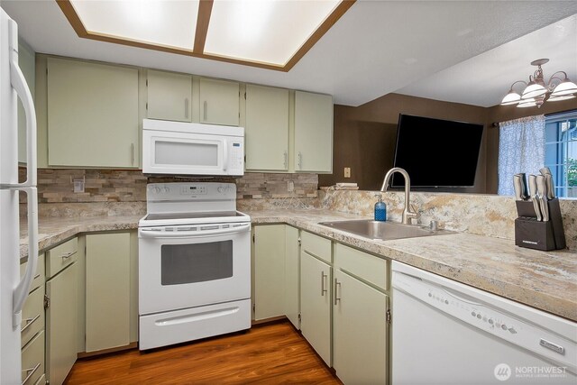 kitchen featuring tasteful backsplash, a sink, white appliances, light countertops, and a notable chandelier