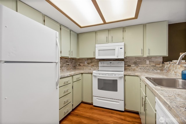 kitchen with light countertops, decorative backsplash, a sink, and white appliances