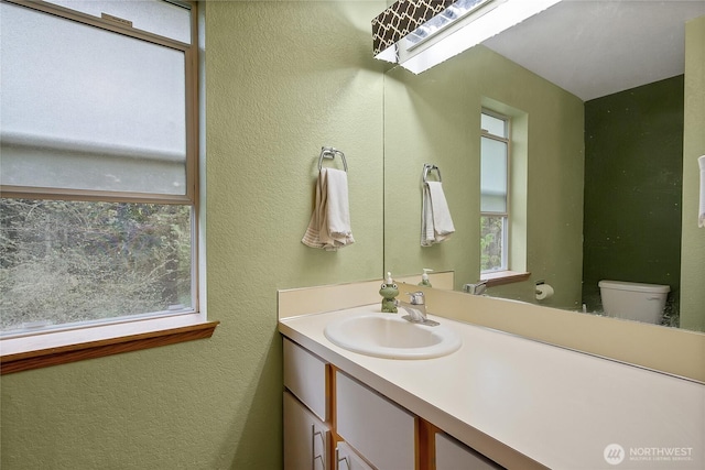 half bath with a textured wall, toilet, and vanity