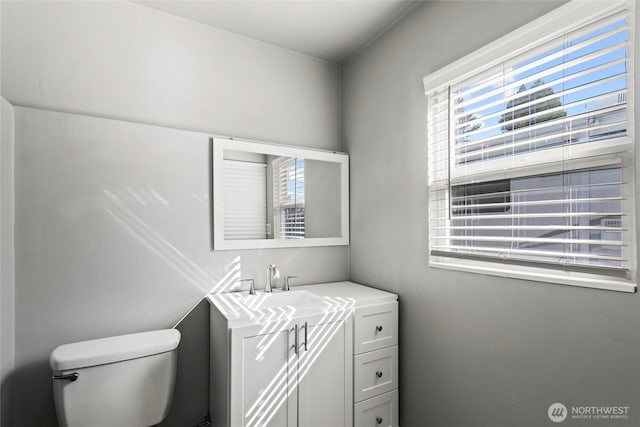 bathroom featuring toilet, vanity, and a healthy amount of sunlight