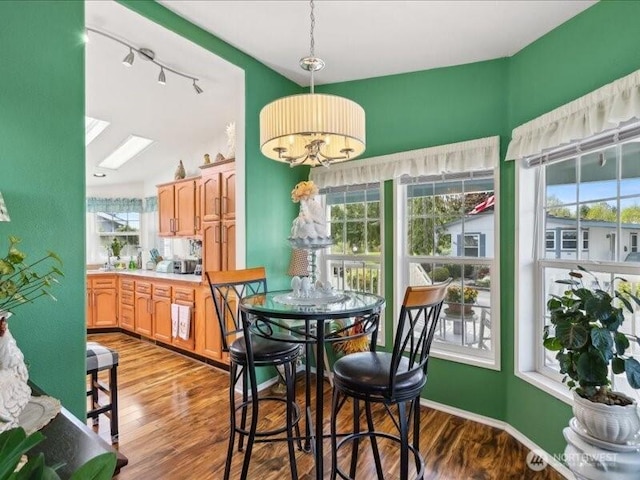 dining space featuring track lighting, wood finished floors, and a chandelier