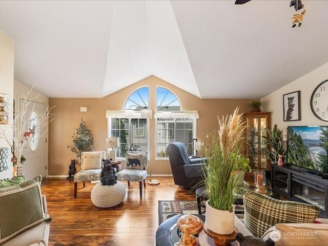 living room featuring vaulted ceiling, a ceiling fan, baseboards, and wood finished floors