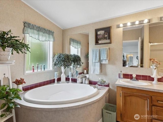 full bathroom featuring a garden tub, lofted ceiling, and vanity