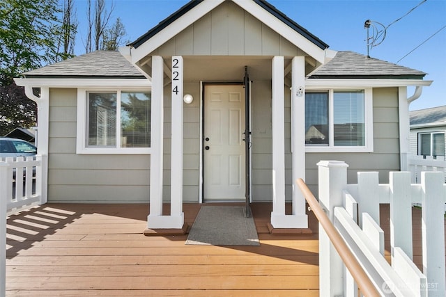 entrance to property with a wooden deck and roof with shingles