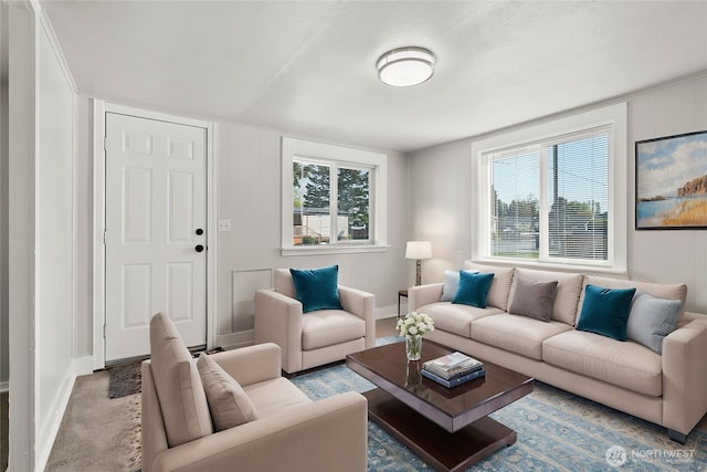 living room with carpet floors, baseboards, and a decorative wall