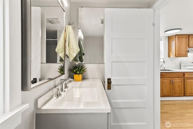 bathroom with wood finished floors, backsplash, and vanity