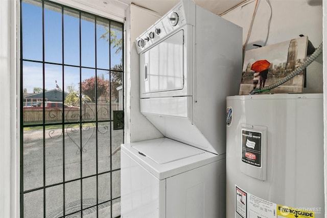 clothes washing area featuring water heater, laundry area, and stacked washer and dryer