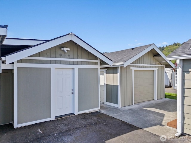 exterior space with driveway, roof with shingles, and a garage