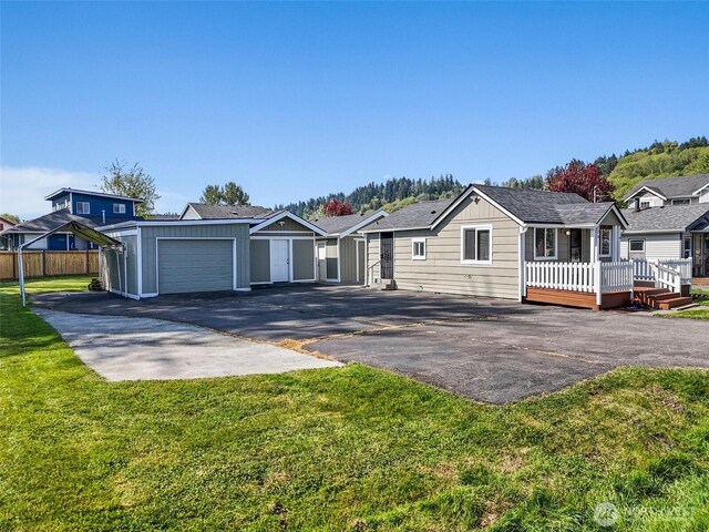 ranch-style home featuring board and batten siding, aphalt driveway, a wooden deck, a garage, and a front lawn