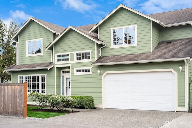 view of front of home featuring fence, an attached garage, concrete driveway, and a shingled roof