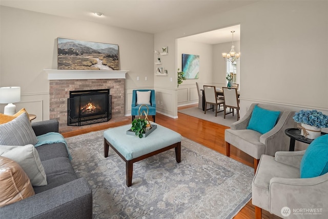 living area with a brick fireplace, wood finished floors, and a chandelier