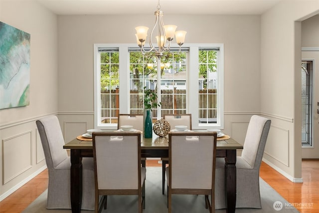dining space featuring an inviting chandelier, a decorative wall, and a healthy amount of sunlight
