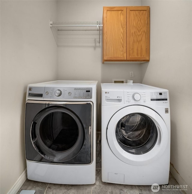 washroom with cabinet space, separate washer and dryer, and baseboards