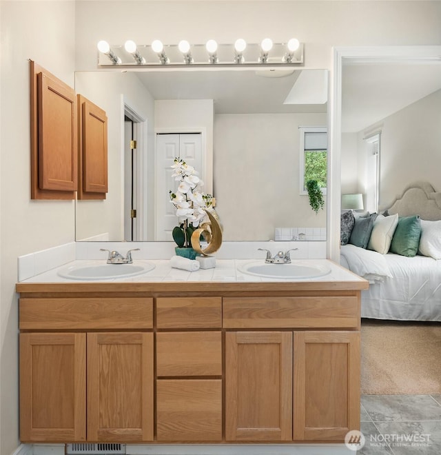 bathroom with ensuite bathroom, a sink, tile patterned flooring, and double vanity