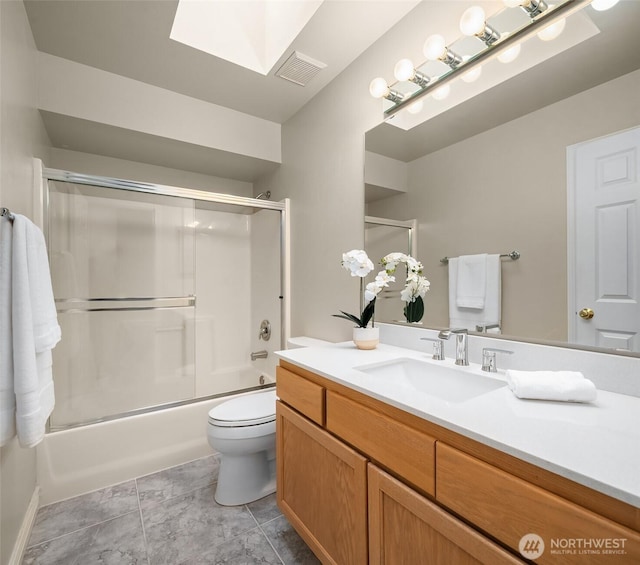 bathroom featuring vanity, toilet, combined bath / shower with glass door, a skylight, and visible vents