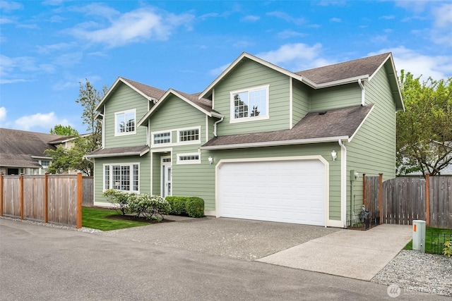 traditional-style home with a garage, fence, driveway, and a shingled roof