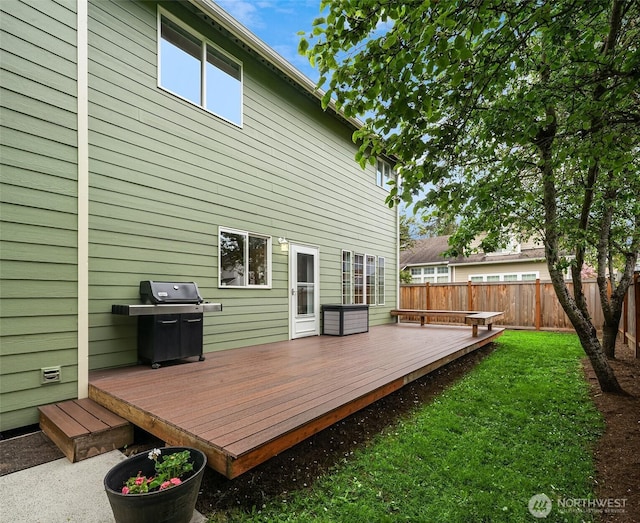 wooden terrace featuring a fenced backyard, a yard, and grilling area