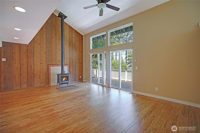 366 Tillicum Way, Camano Island, WA 98282 - unfurnished living room featuring a ceiling fan, high vaulted ceiling, wood walls, a wood stove, and light wood-style floors
