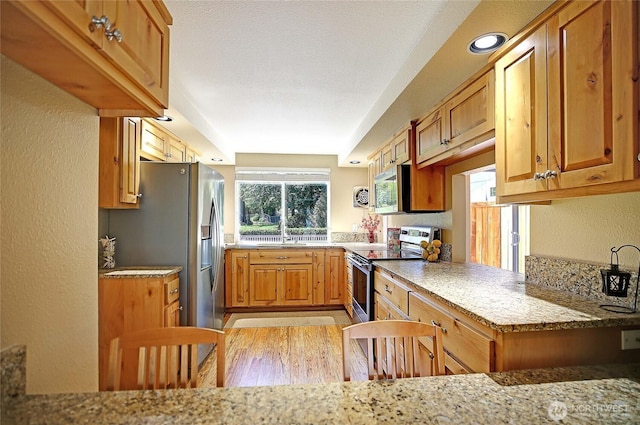 366 Tillicum Way, Camano Island, WA 98282 - kitchen with light stone countertops, stainless steel appliances, brown cabinets, and light wood-style floors