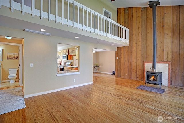 366 Tillicum Way, Camano Island, WA 98282 - unfurnished living room with a wood stove, baseboards, light wood-style flooring, and a towering ceiling