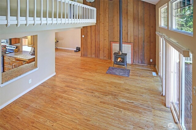 366 Tillicum Way, Camano Island, WA 98282 - interior space with light wood finished floors, high vaulted ceiling, baseboards, a wood stove, and wooden walls