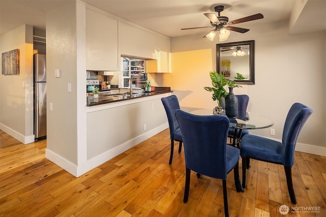 dining area featuring a ceiling fan, baseboards, and light wood-type flooring