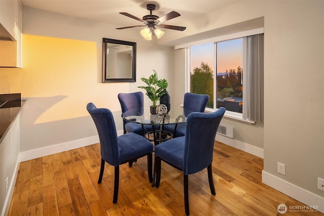dining space with baseboards, a ceiling fan, and light wood-style floors