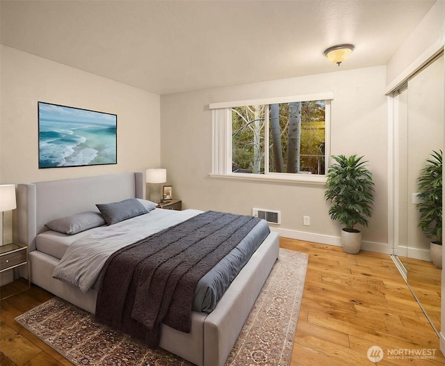 bedroom featuring baseboards, visible vents, and wood-type flooring