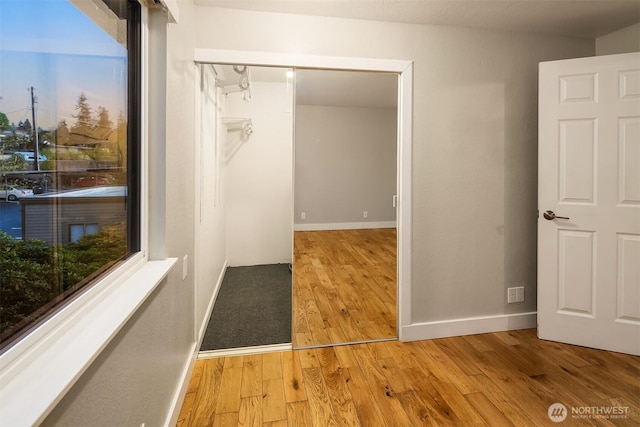 hallway featuring plenty of natural light, light wood-style flooring, and baseboards